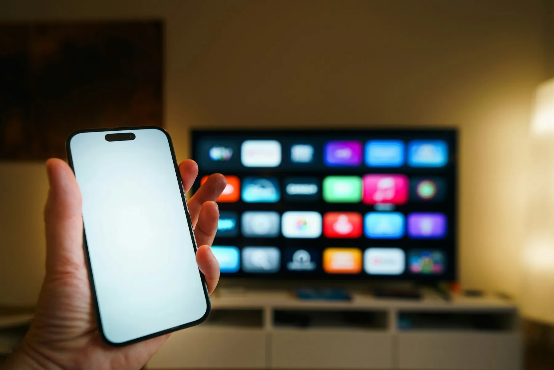 A phone held up in front of a smart TV, both showing streaming content